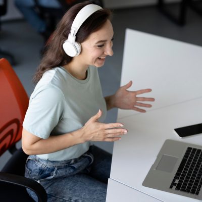 Women at work wearing headphones in front of a laptop